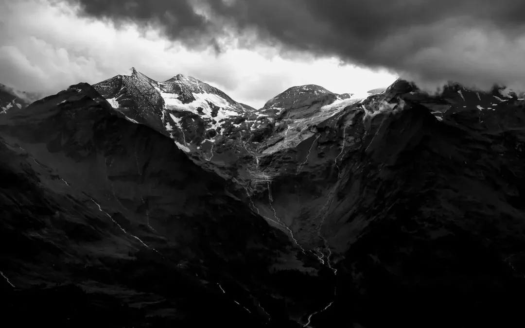 Black and white mountain range under heavy cloud